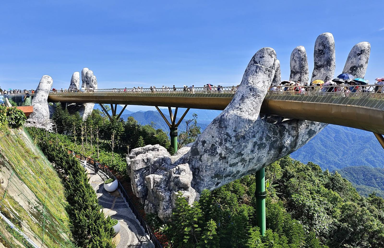 The Golden Bridge held up by two giant stone hands at Ba Na Hills above Da Nang on a sunny day