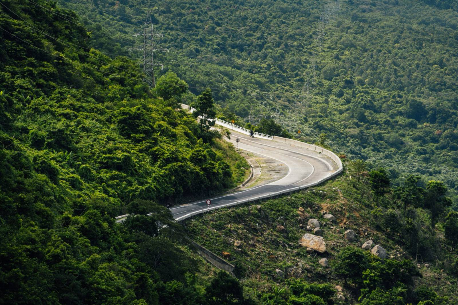 The Hai Van Pass road curving through green forest on the mountain between Hue and Da Nang on a sunny day