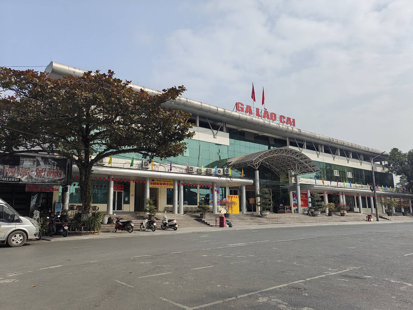 The front of Lao Cai railway station with its red GA LAO CAI sign under a pale blue sky on a clear afternoon