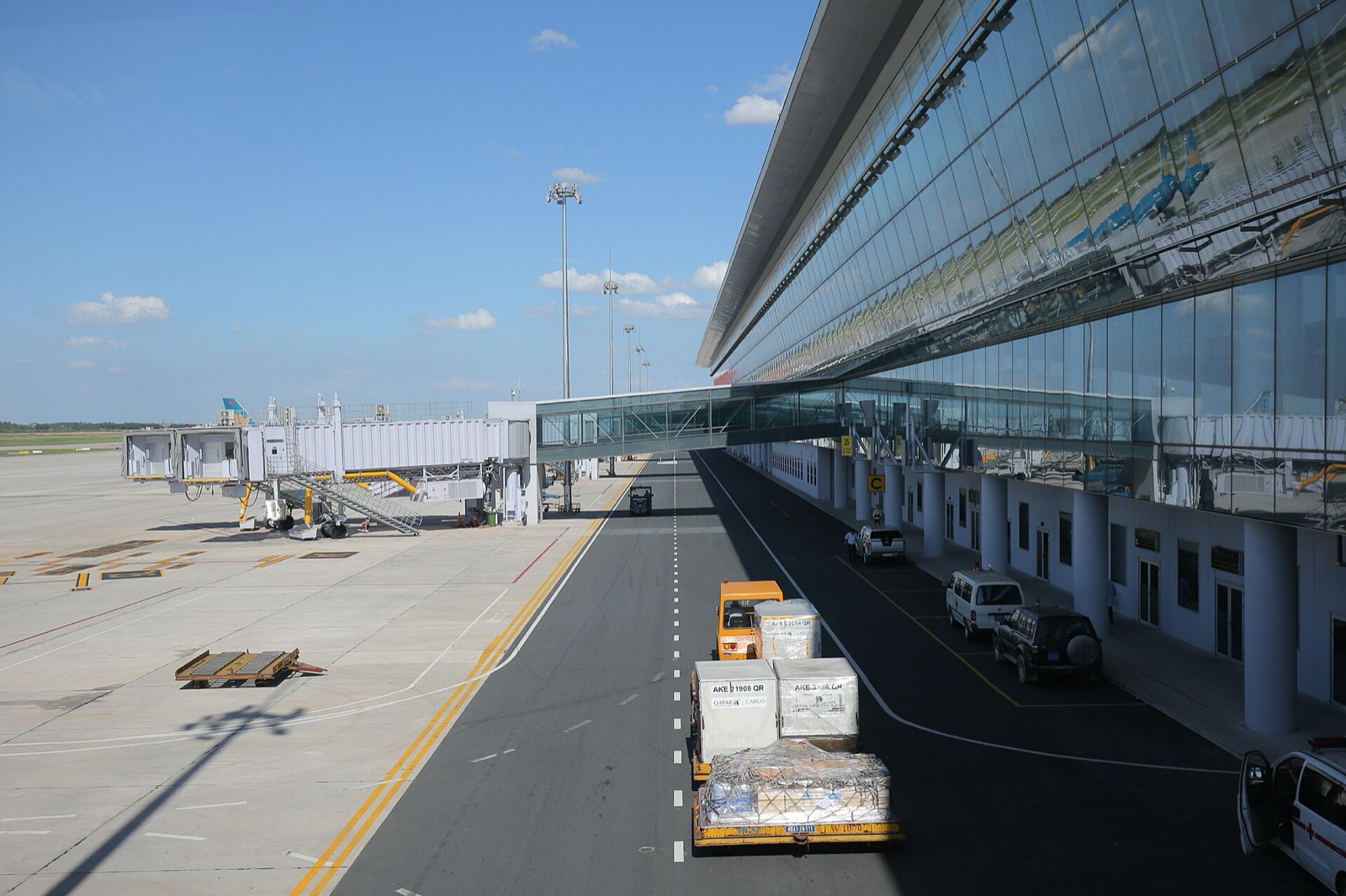 The long glass facade of Noi Bai International Airport's Terminal 2 beside the apron and jet bridges under a blue sky