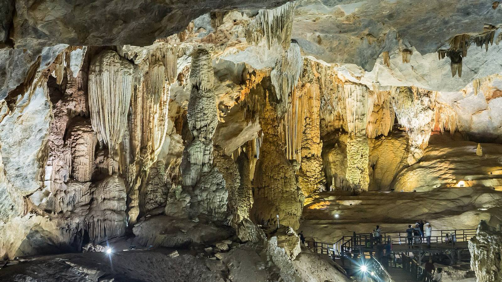Lit stalactites and stalagmites inside Paradise Cave in Phong Nha-Ke Bang National Park, with visitors on a wooden walkway