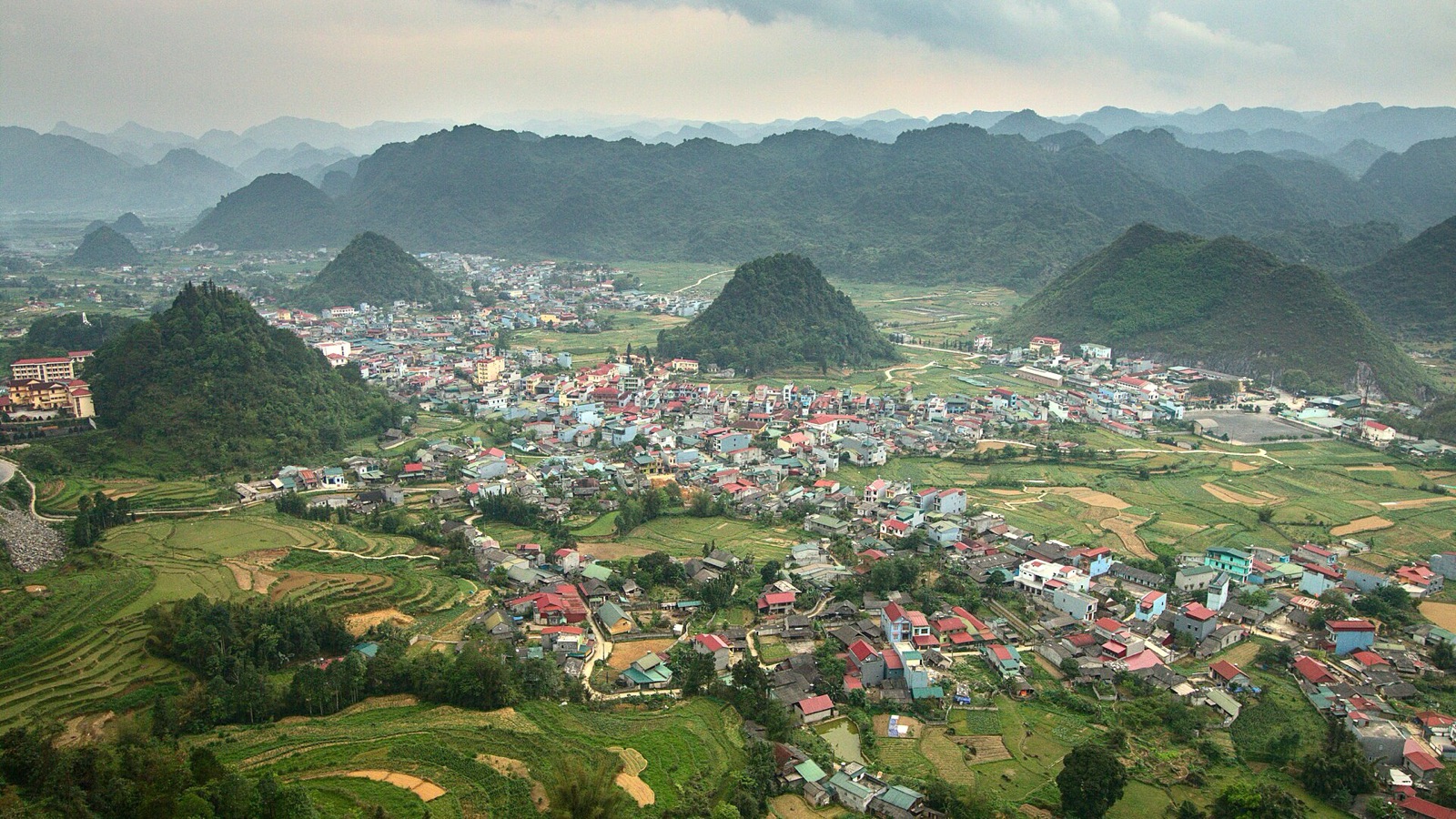 Tam Son town and the cone-shaped green hills of the Quan Ba valley in Ha Giang, seen from the mountain road above it in daylight
