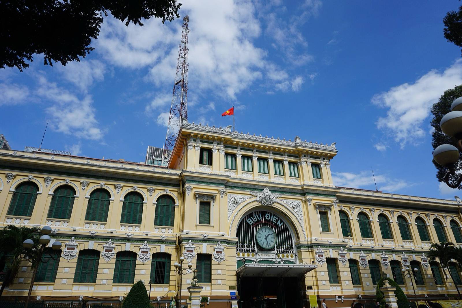 The yellow facade and clock of Saigon Central Post Office in Ho Chi Minh City under a blue sky