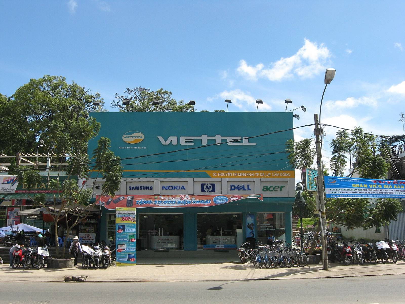 A Viettel mobile phone shop with a teal facade and large white lettering on Nguyen Thi Minh Khai Street in Da Lat under a blue sky